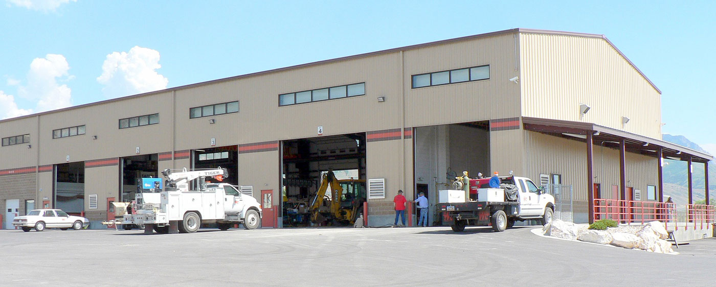 an industrial building with  an excavator and trucks