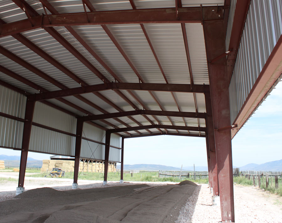 a red steel hey barn in a rural area with white dirt