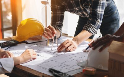Project manager discussing construction plans with workers while examining blueprints